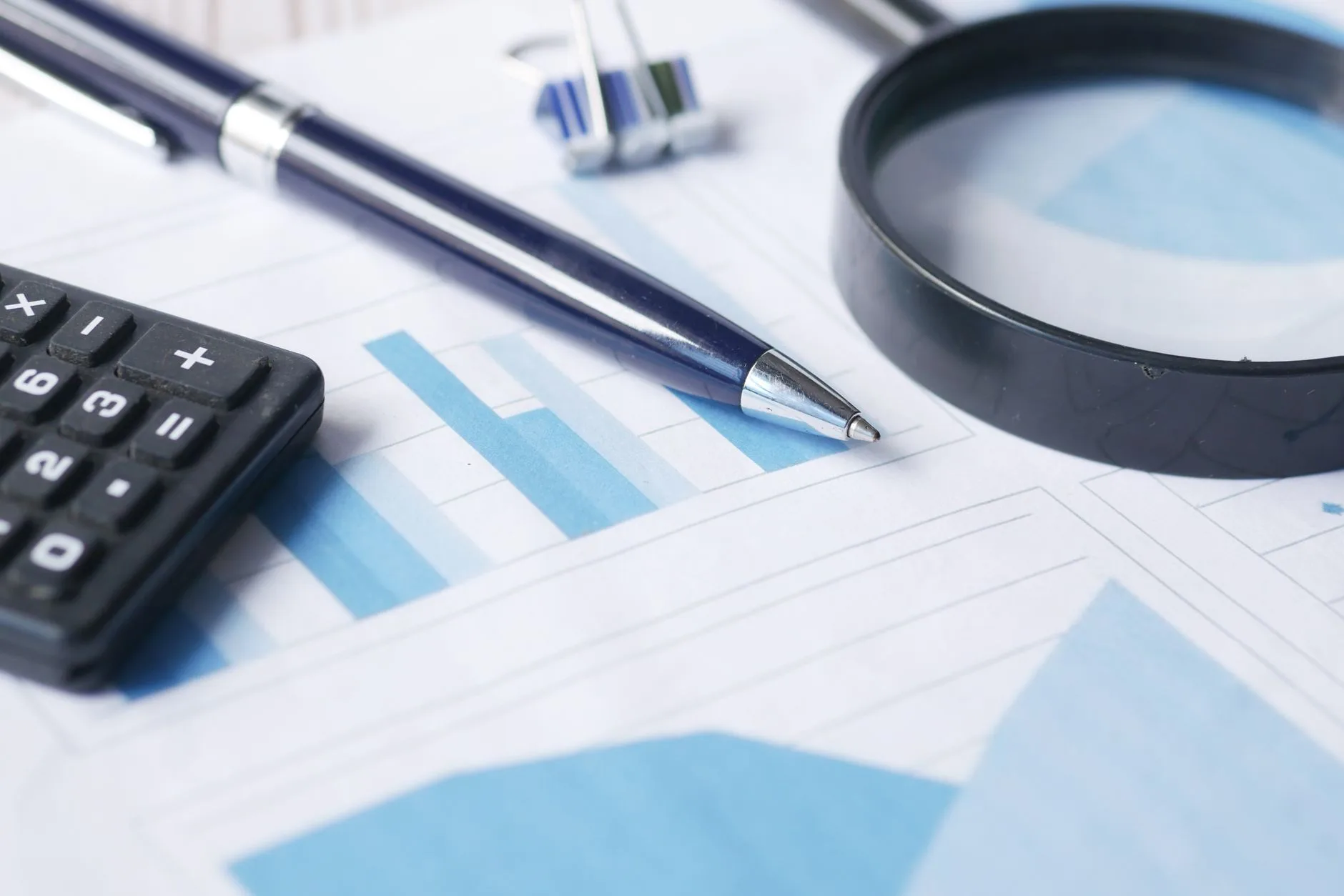 Loupe, calculatrice et stylo posés sur un graphique en barres — symbole de filtrage et d'analyse d'une liste de prospects.