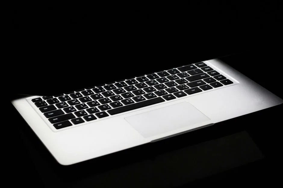 Un ordinateur portable éclairé dans le noir : un message de prospection qui part sans jamais être vu.