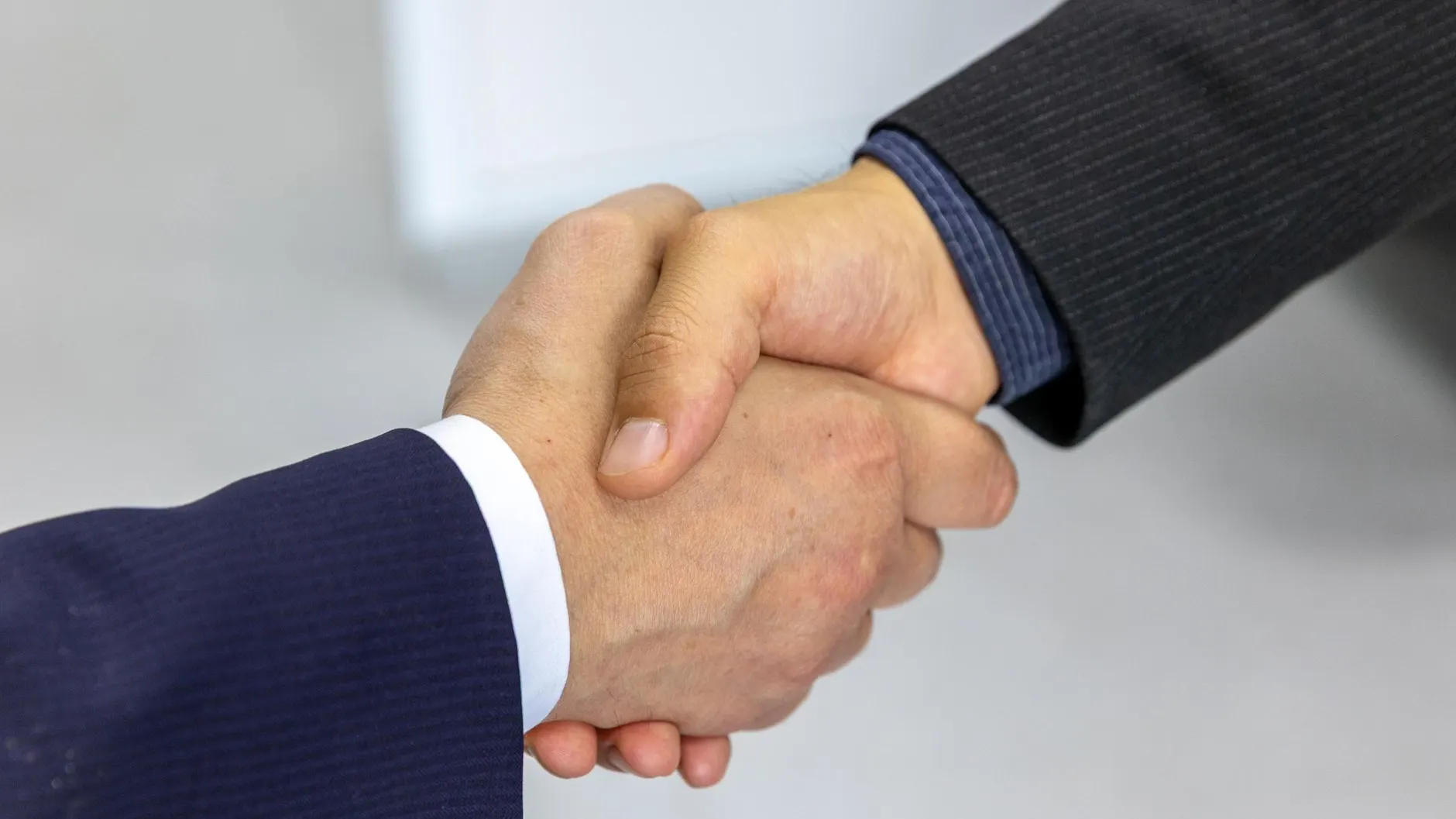 Poignée de main entre deux professionnels en costume, gros plan sur les mains — symbole d'une connexion acceptée.