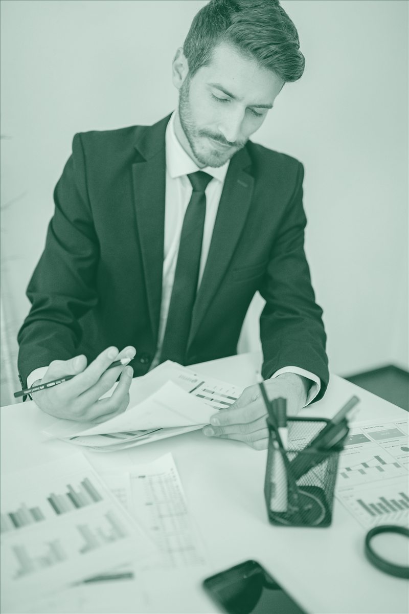Dirigeant d'organisme de formation analysant des tableaux de chiffres et des graphiques financiers.
