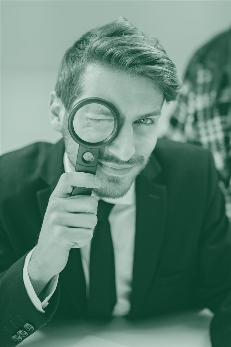 Dirigeant observant à la loupe, image de la recherche de prospects pour un organisme de formation.